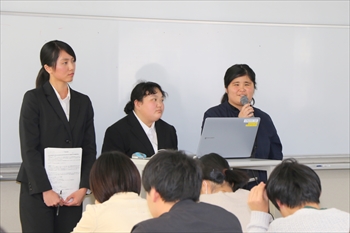 写真：3名の学生が参加者の前に立って発表を行う様子