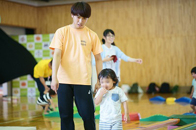 写真：遊具で遊ぶ子どもの安全を見守る男子学生