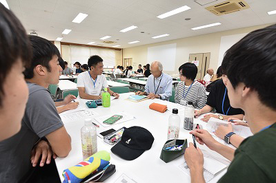 写真：学生グループのグループワークに参加しする町内会住民。その住民を囲んで話をする学生