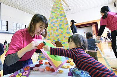 写真:手作りのおもちゃを使って子どもと遊ぶ学生
