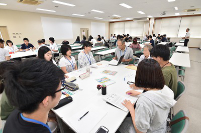 写真：学生グループのグループワークに参加しする町内会住民。その住民を囲んで話をする学生