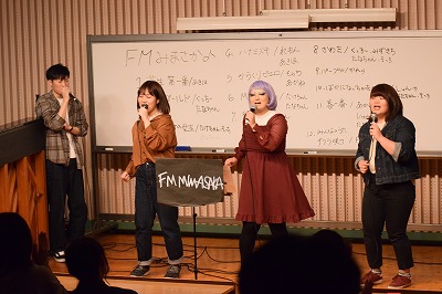 ステージで楽器を演奏し歌う学生