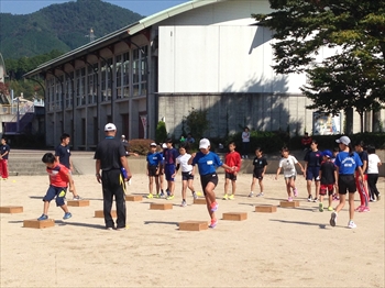 写真：障害物の上を跳んだりまたいだりしてトレーニングをする小学生