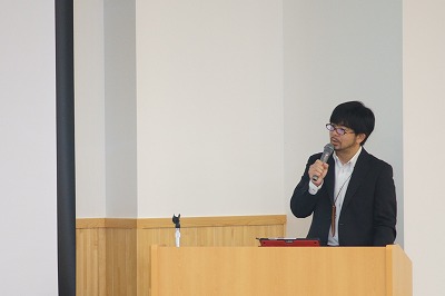 写真：全体会で概要説明をする武田准教授