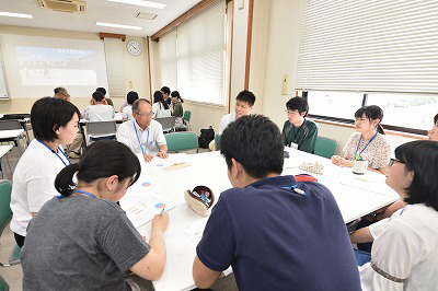 写真：学生グループのグループワークに参加しする町内会住民。その住民を囲んで話をする学生
