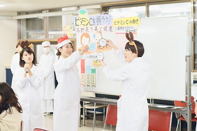 写真：資料を提示して、説明する栄養教育担当の学生。学生同士の掛け合いの様子