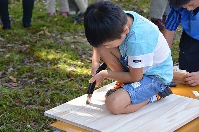 ノコギリで木を切る子ども