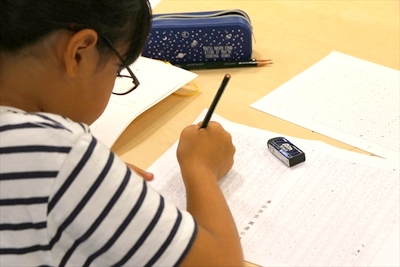 写真：原稿用紙を前に、熱心に感想文を書く小学生