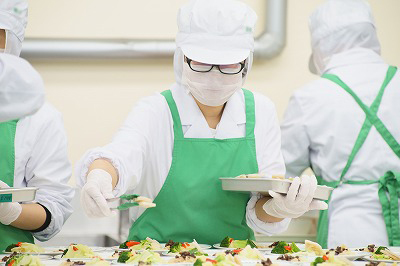 写真：調理担当の学生が丁寧に盛り付ける様子