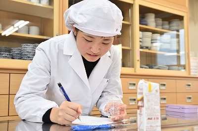 写真：試食の感想などを熱心にメモをする学生
