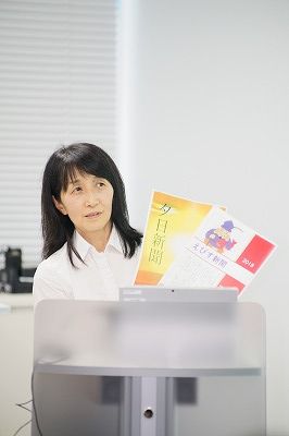 写真：出来上がった情報紙を2つ手に講評を話す岸田先生