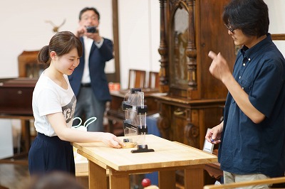 写真：ビー玉が落ちてくる場所を予想して受け皿を置く学生