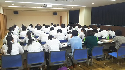 写真：入所者の方から話を聞く学生。後ろから