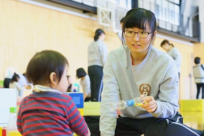 写真：手作りのおもちゃを使って遊ぶ学生と子ども