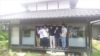 写真：民家の縁側に立つ男子学生