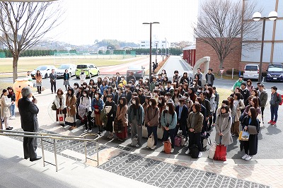 写真：階段でスピーチする教員とそれを聞く学生