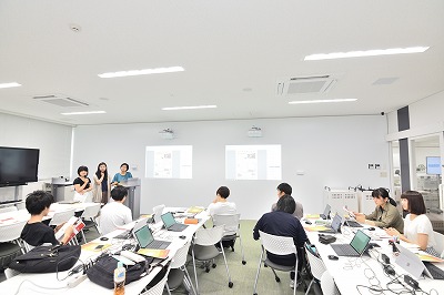写真：一つのグループの発表の様子。3名で演台の前で発表する姿
