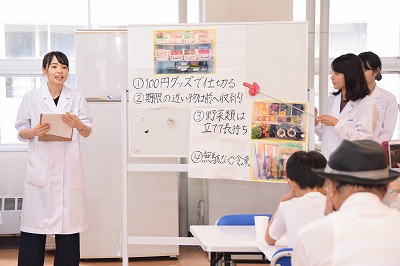 白衣を着た学生が講義をする様子