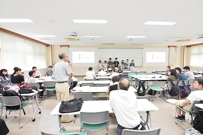写真：アンケート調査の発表を終えた学生グループに質問をする町内会の住民。立って質問する姿
