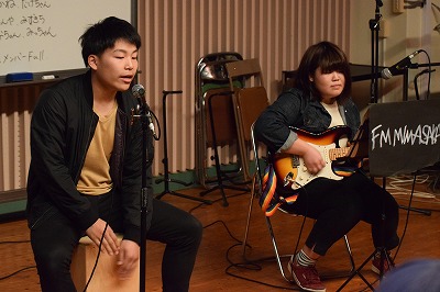 ステージで楽器を演奏し歌う学生