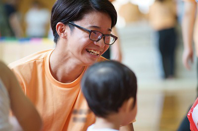写真：手作り遊具で子どもたちと笑顔で遊ぶ学生