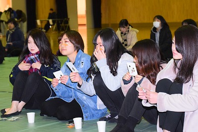 写真：ビンゴ大会の様子。自分のビンゴカードの番号をチェックする参加者