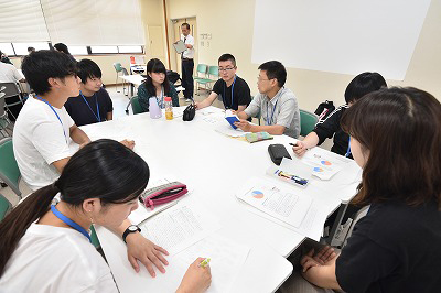 写真：学生グループのグループワークに参加しする町内会住民。その住民を囲んで話をする学生