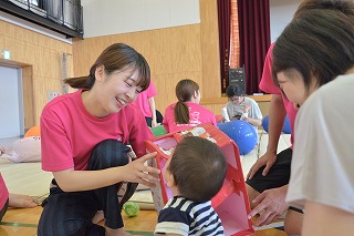 写真:手作りのおもちゃを使って子どもと遊ぶ学生
