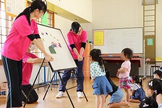 写真：ホワイトボードシアターを行う学生とそれを見る子ども