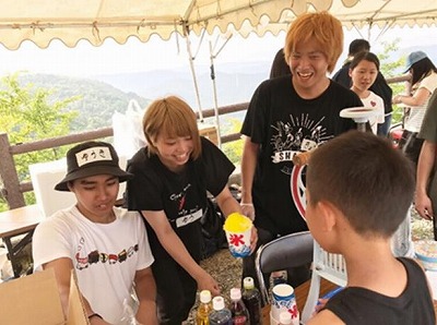 写真：屋台テントでお客にレモンのかき氷を出すスタッフ
