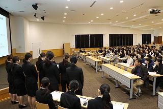 写真：発表する4年生と聴講する教員、3年生