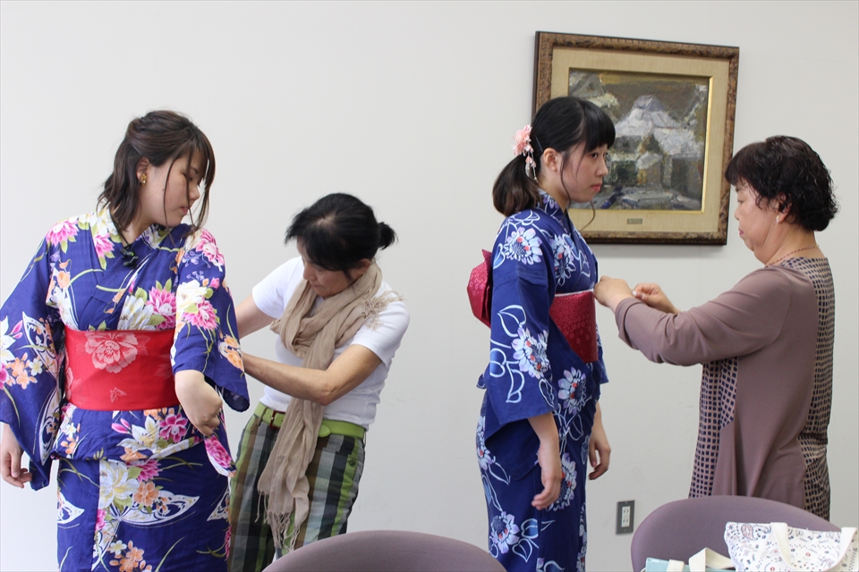 写真：浴衣の着付けをする同窓会生と、着つけてもらう学生