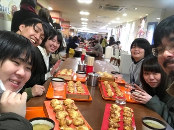 写真：明石風たこ焼きを前に微笑む学生と武田准教授
