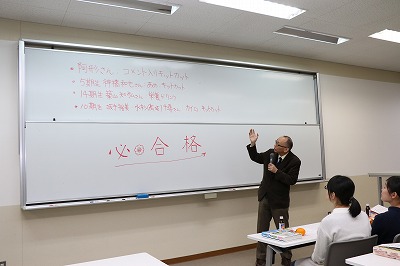 写真：ホワイトボードを示しながら話す教員