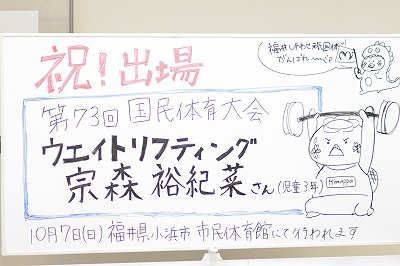 写真：職員がホワイトボードに書いた激励のイラスト付き紹介ボード