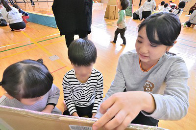 写真：手作りの遊具で遊ぶ学生とこども