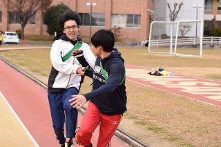 写真：リレーでバトンの受け渡しをする学生