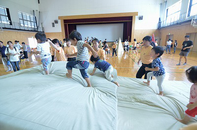 写真：ソフトマットの丘を越える子どもたちと安全に配慮しながら見守る学生たち