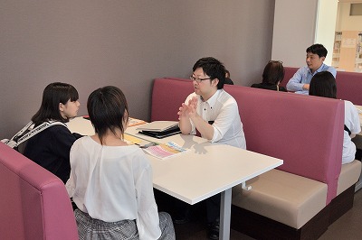 写真：個別相談ブースで相談する参加者と保護者。対応する職員