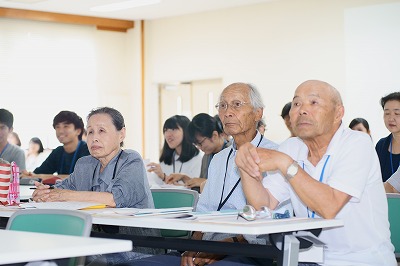 写真：アンケート調査の発表を真剣な表情で聞く町内会の住民3名