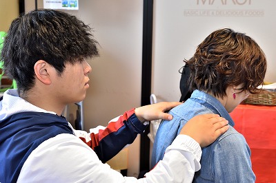 写真：リラクゼーションの場を提供。学生1人が買い物客1人にリラクゼーションマッサージを実施する様子