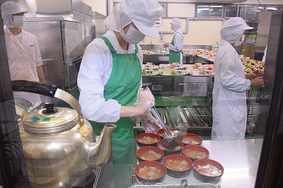 写真：汁物の豚汁を器につぐ学生