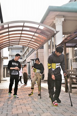 写真：片マヒ体験をする学生2人と介助役の学生