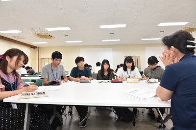 写真：学生グループのグループワークに参加しする町内会住民。その住民を囲んで話をする学生