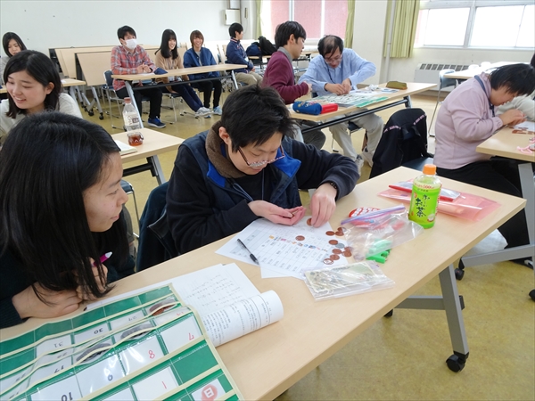 写真：参加者の隣に座って参加者をサポートする学生