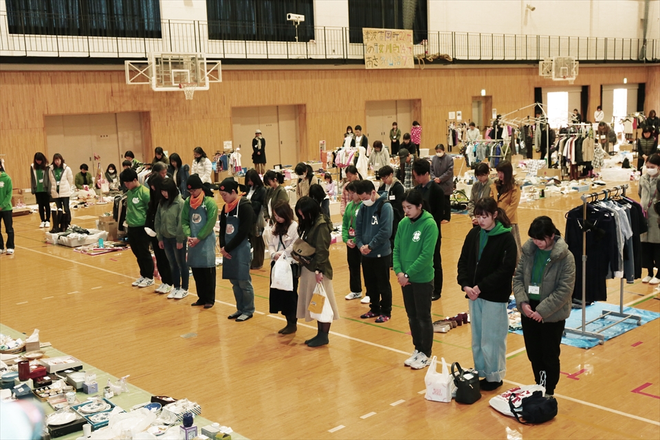 写真：その場に立って黙とうをささげる学生スタッフと地域の方