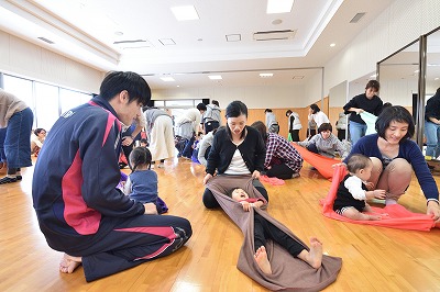 写真:タオルを使った触れ合い遊びを試す親子