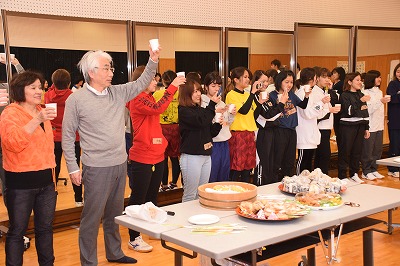 顧問の先生と学生が乾杯をする姿