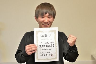 写真：優勝した賞状を手にガッツポーズをする伏見くん