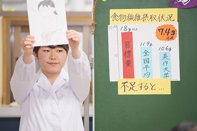 写真：資料を提示して、説明する栄養教育担当の学生